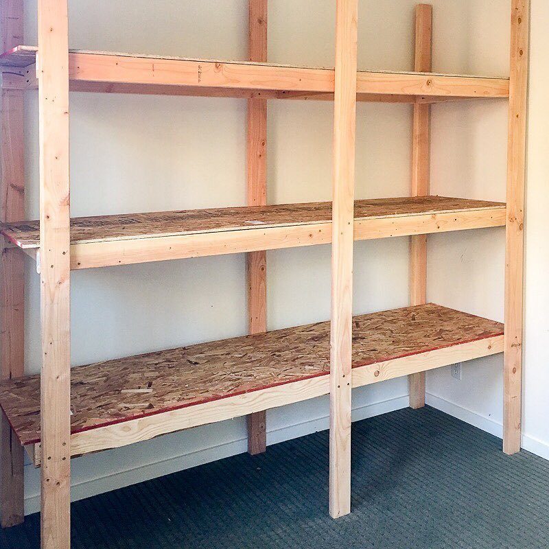 Unfinished wooden storage shelves made from 2x4 lumber and OSB particle board.