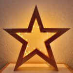Large wooden star decoration with warm yellow fairy lights glowing inside.