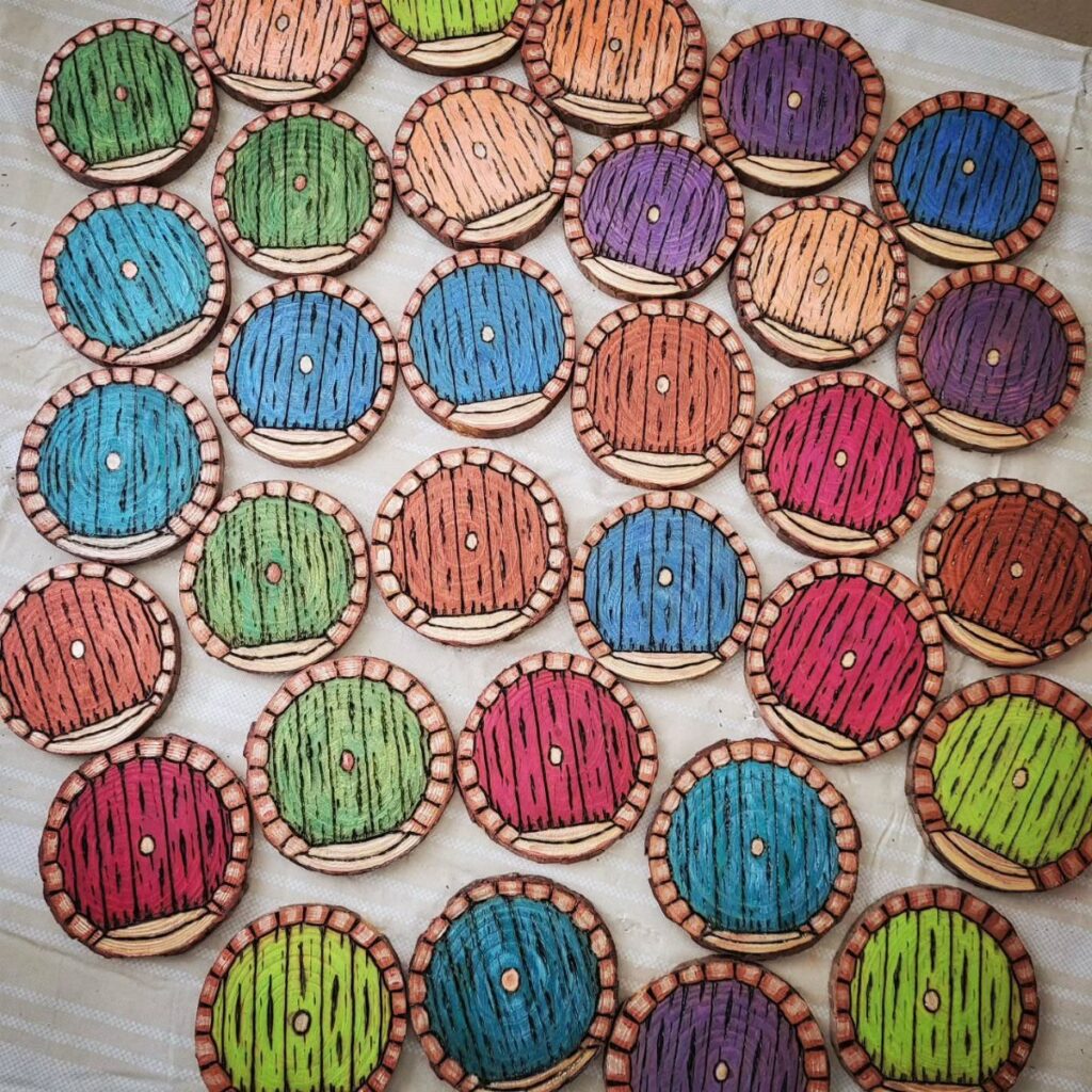 Colorful burned wood slice art circles arranged on a white cloth background.