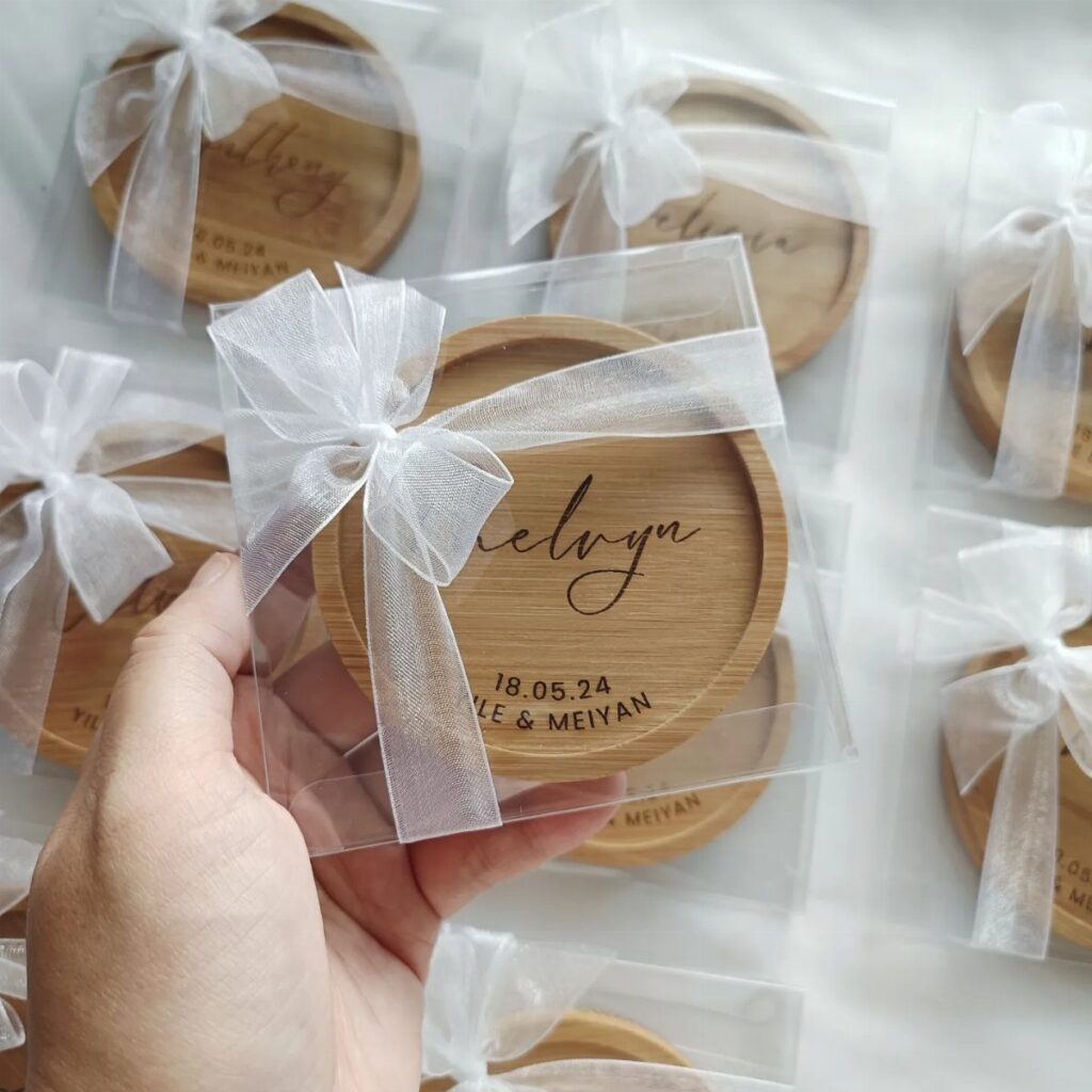 Circular wooden coasters with engraved names and dates wrapped in white ribbons