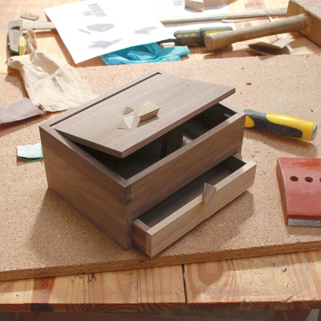 Handmade wooden jewelry box with drawer on a workbench with woodworking tools