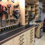 Miter saw integrated into a custom wooden storage cabinet with a black countertop.