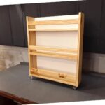 Wooden child's bookshelf with three shelves and caster wheels on a workbench.