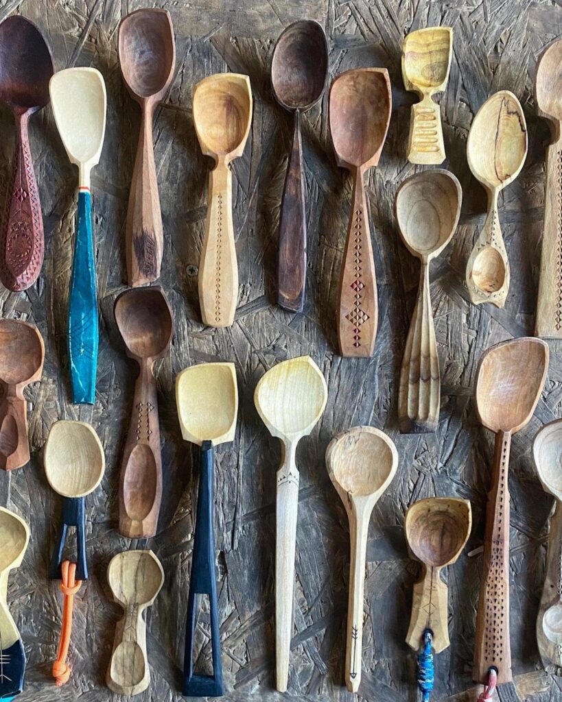 Hand-carved wooden spoons of various sizes and colors on a dark textured background.