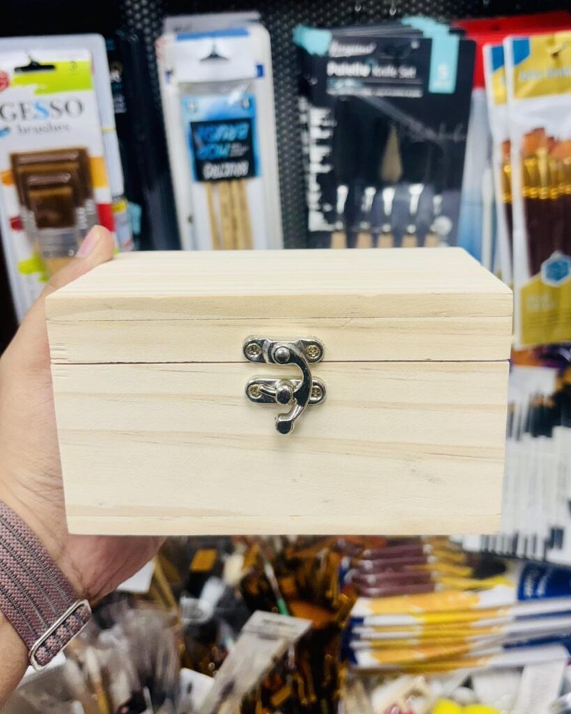 Small natural wood box with silver clasp held in a person's hand.