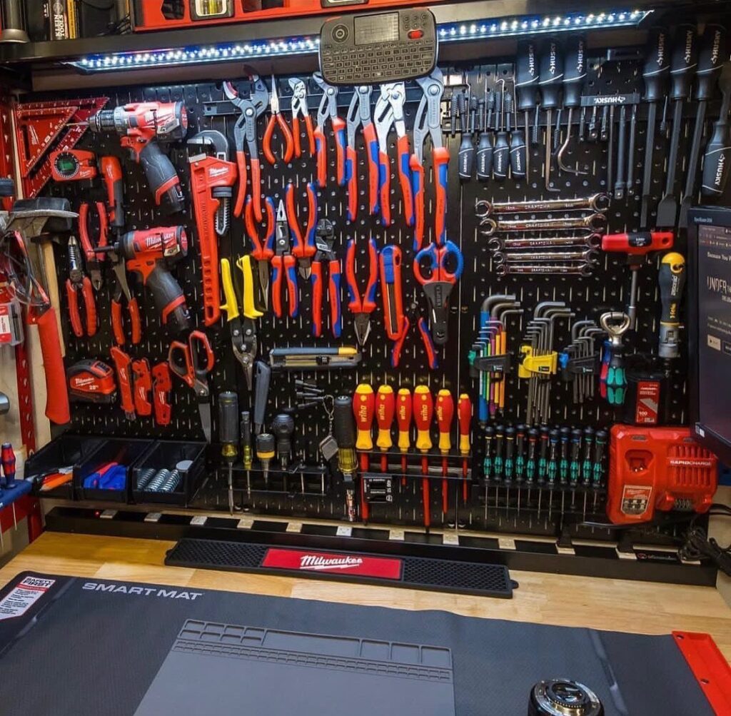 Black metal pegboard wall organized with a wide variety of professional hand tools.