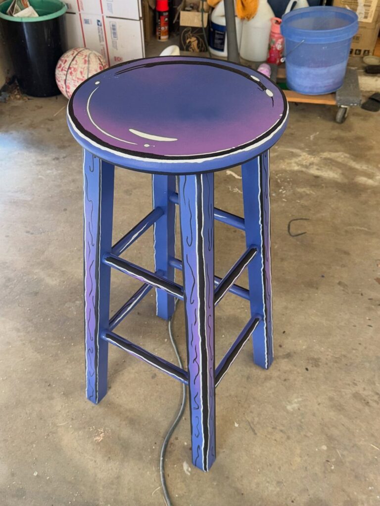 Cartoon style painted wooden stool with purple seat and blue legs in a garage.