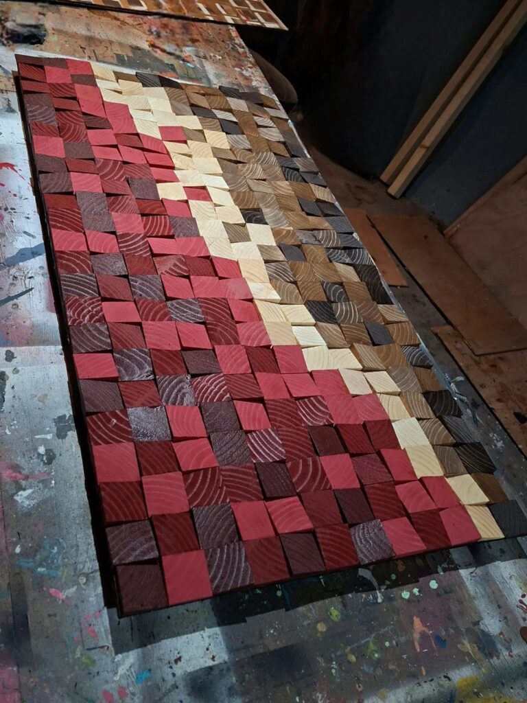 Wooden block mosaic with red and brown squares on a workshop table.