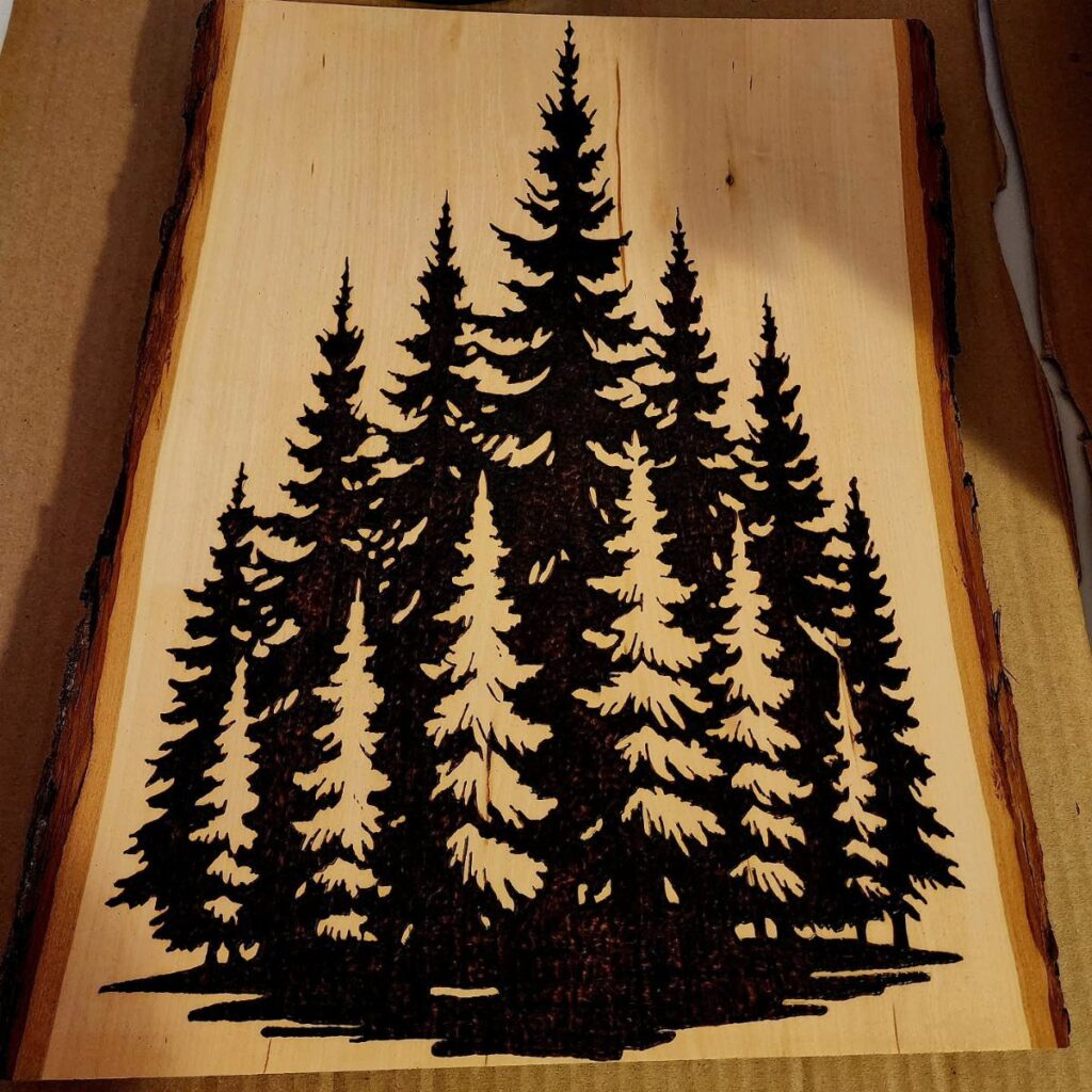 Wood burned pine trees on a light natural wood slab with live edges.