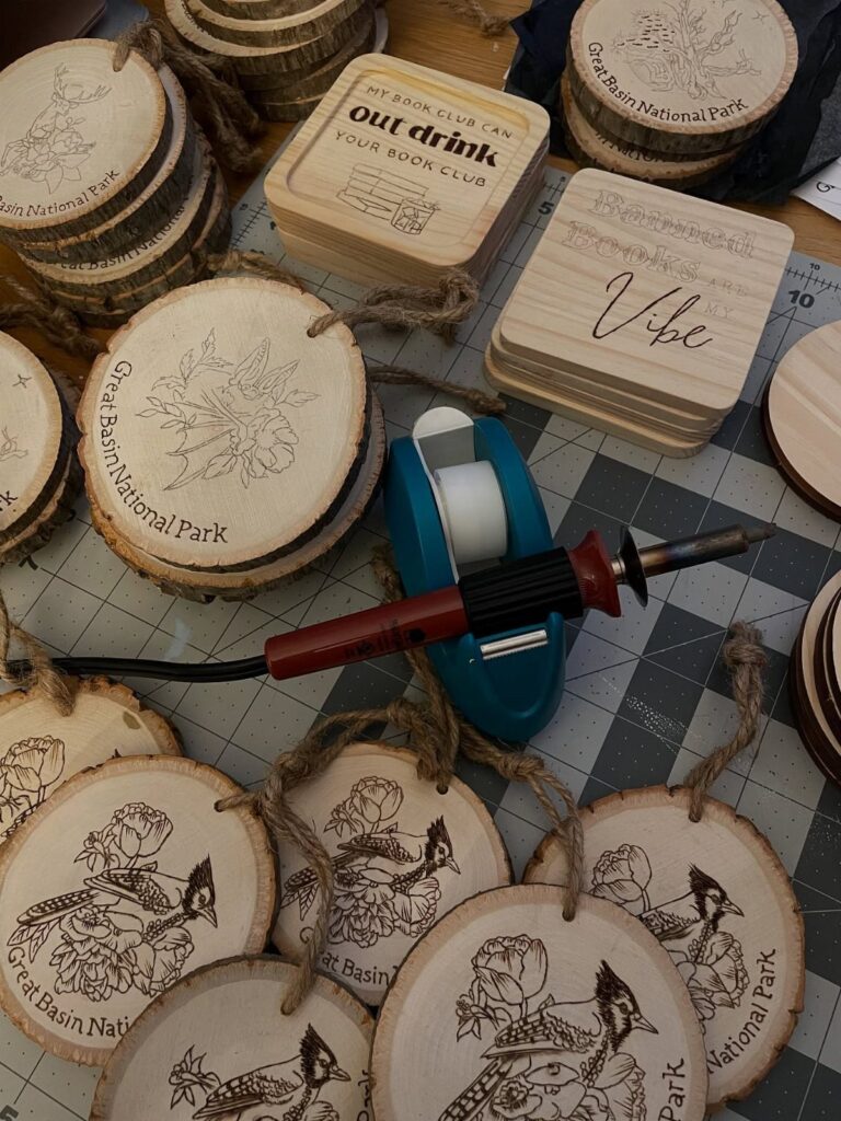 Wood burning tool and circular wood slice ornaments with pyrography bird designs.