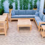 Wooden outdoor lounge set with blue cushions and a coffee table on a deck.