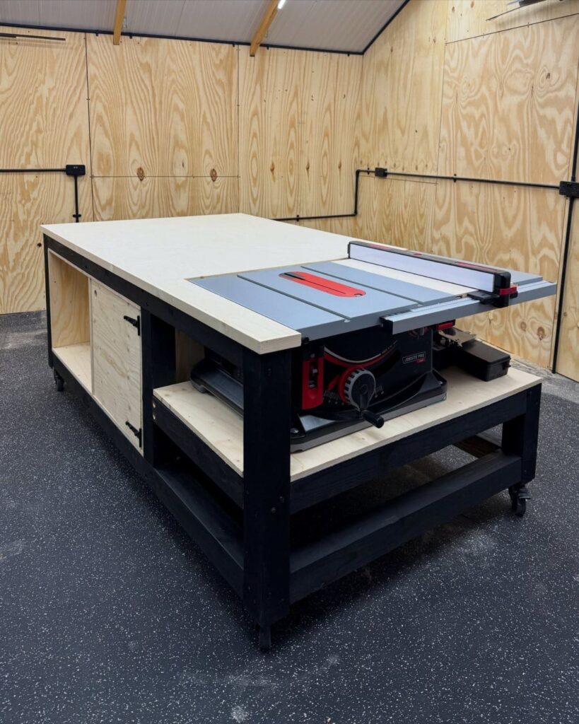 Woodworking workbench with integrated table saw in a plywood walled workshop