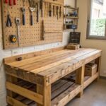 Wooden pallet workbench with a tool-filled pegboard mounted on the wall above it.